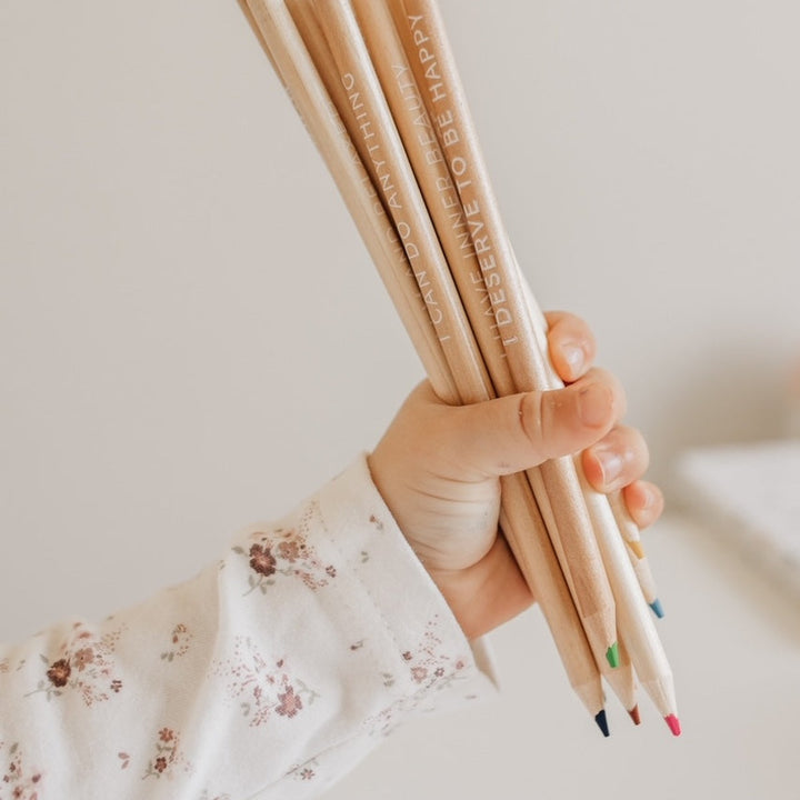 Child holding a handful of affirmation colouring pencils with coloured tips
